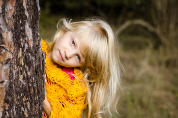 Naklejka premium beautiful child behins tree trunk in the forest