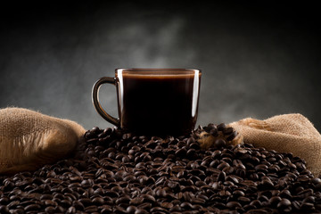 A cup of coffee on coffee beans with jute