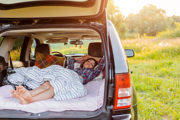 woman sleeps comfortably her car Luggage compartment nature summer under blanket. concept...