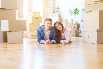 Fototapeta na wymiar Young beautiful couple relaxing lying on the floor around cardboard boxes at home, smiling happy moving to a new house