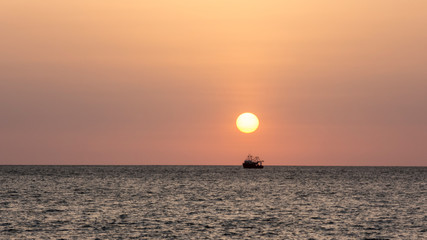 sunset over the sea with a boat
