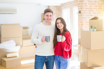 Fototapeta na wymiar Beautiful young couple smiling in love drinking a cup of coffee celebrating moving to a new home