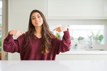 Young beautiful woman at home looking confident with smile on face, pointing oneself with fingers...