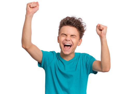 Portrait of successful teen boy winner with raised hands and clenching fists. Beautiful caucasian teenager shouting, isolated on white background. Happy cute child celebrating success with joy.