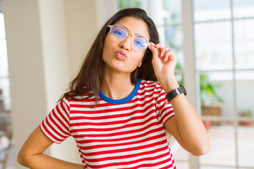 Beautiful young woman wearing glasses and posing sending a kiss and doing funny faces