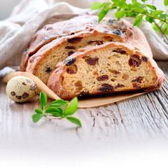 Easter bread, close-up on traditional fruty bread on rustic wood with fresh leaves and quail egg