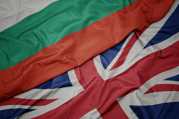waving colorful flag of great britain and national flag of bulgaria.