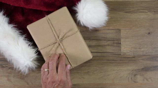 Soldiers hands place a Christmas Present on a table with a Santa Hat