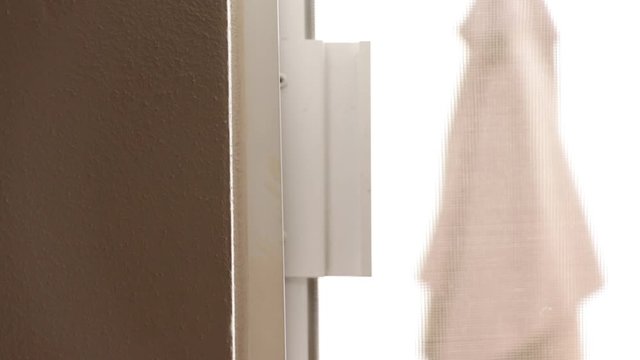 Detalle de una mano abriendo una ventana blanca corrediza con manija negra