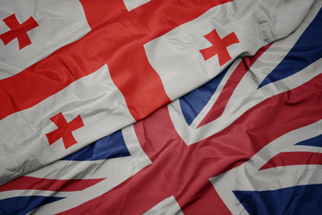 Fototapeta premium waving colorful flag of great britain and national flag of georgia.