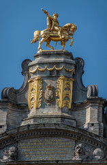 Fototapeta na wymiar Brussels, Belgium - June 22, 2019: Closeup of gulden statue of Charles Alexander of Lorraine on top of L’Arbre D’Or house on Grand place against blue sky.