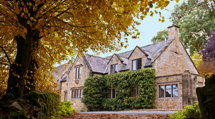 English Cotswold's Stone House and autumn colored trees.