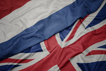 waving colorful flag of great britain and national flag of netherlands.