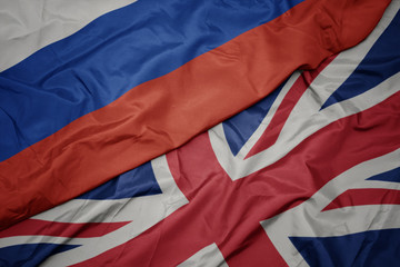 waving colorful flag of great britain and national flag of russia.