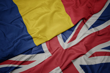 waving colorful flag of great britain and national flag of romania.