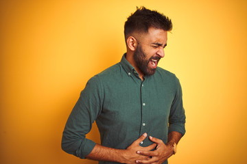 Young indian businessman wearing elegant shirt standing over isolated white background with hand on stomach because indigestion, painful illness feeling unwell. Ache concept.