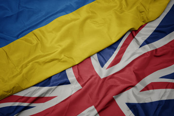waving colorful flag of great britain and national flag of ukraine.