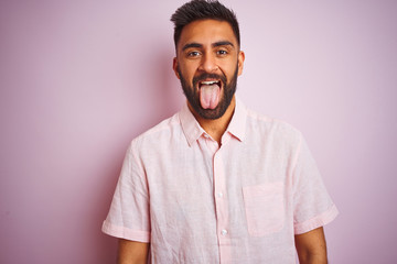 Young indian man wearing casual shirt standing over isolated pink background sticking tongue out happy with funny expression. Emotion concept. © Krakenimages.com