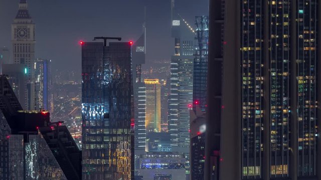 Dubai International Financial Centre district with illuminated modern skyscrapers night timelapse. Aerial view from Downtown with traffic on streets