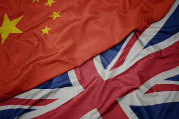 waving colorful flag of great britain and national flag of china.