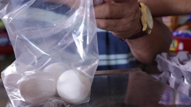Manos de hombre colocando huevos blancos en una bolsa de pl&aacute;stico