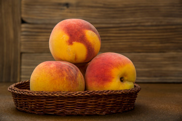 Naklejka na ściany i meble Peaches in a wicker basket on rustic background
