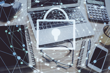 Double exposure of desktop with computer and lock icon hologram. Concept of data safety.