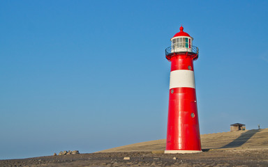 Red-white lighthouse in front of the North Sea dike.