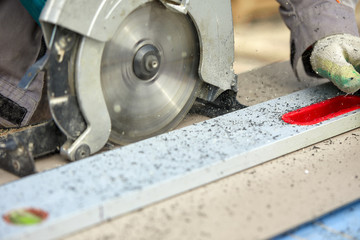 A construction contractor worker using a worm-driven hand-held circular saw to cut boards and plastic. Construction concept, own workshop, hiring a working contract for cutting wood.
