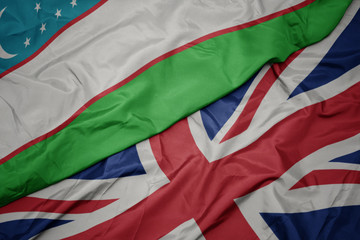 waving colorful flag of great britain and national flag of uzbekistan.