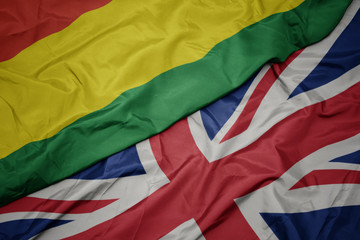 waving colorful flag of great britain and national flag of bolivia.