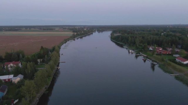 Flying over river with boats and village. Arial drone shot. Water. Ripples and waves. Coast and wild forest.
