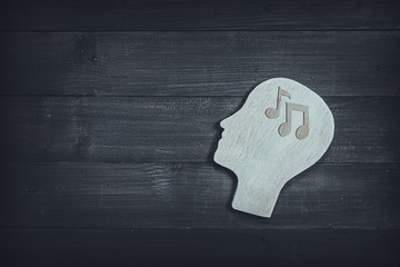 Human head and face with music note sign on wood table background. Brain of thinking about music ,...
