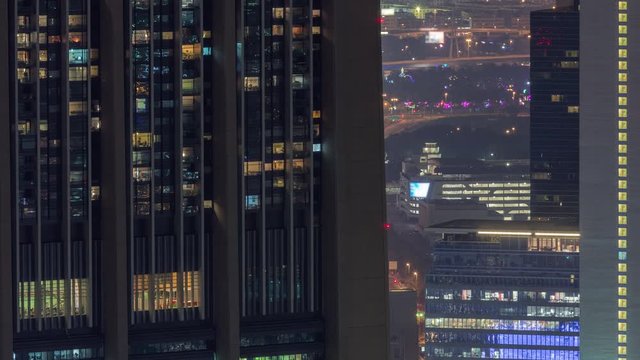 Dubai International Financial Centre district with illuminated modern skyscrapers night timelapse. Aerial view from Downtown with traffic on streets and blinking windows on tower