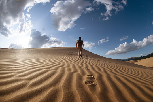 Lonely man walks in desert dunes - Powered by Adobe