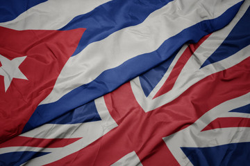 waving colorful flag of great britain and national flag of cuba.