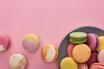 plate with multicolored fresh delicious French macaroons on pink background