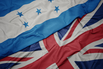 waving colorful flag of great britain and national flag of honduras.