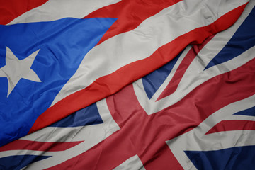 waving colorful flag of great britain and national flag of puerto rico.