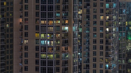 Fototapeta na wymiar Windows of the multi-storey building with lighting inside and moving people in apartments timelapse.