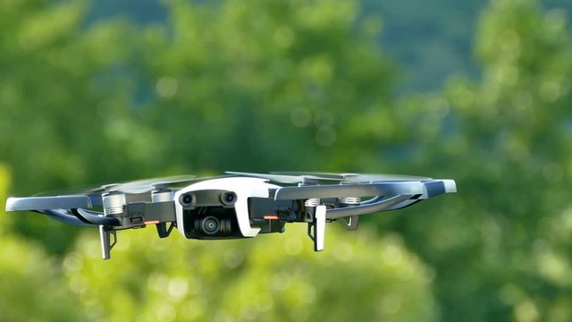 Quadrocopter in the air watching. Drone flies in nature on a green background. Filming from the air.