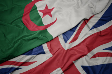 waving colorful flag of great britain and national flag of algeria.