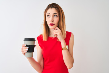 Young beautiful redhead woman drinking take away coffee over isolated white background serious face...