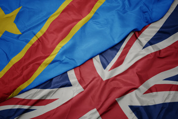 waving colorful flag of great britain and national flag of democratic republic of the congo.