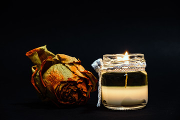 candle and dry rose isolated on black background, liquid wax, small and cute jar