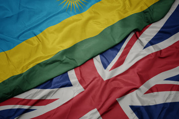 waving colorful flag of great britain and national flag of rwanda.