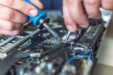 Fototapeta na wymiar a man repairs a computer, solders a board, repairs electronics and modern technologies