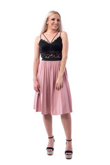 Cheerful young blonde woman in salmon color pleated skirt and lace top looking away. Full body isolated on white background. 