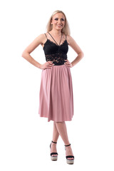 Cheerful relaxed young blonde woman in pleated skirt and lace top smiling and looking away. Full body isolated on white background. 