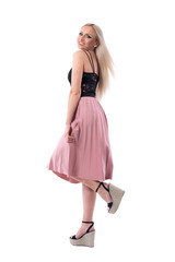 Joyful happy young woman posing in salmon pleated skirt and lace top with raised leg. Full body isolated on white background. 